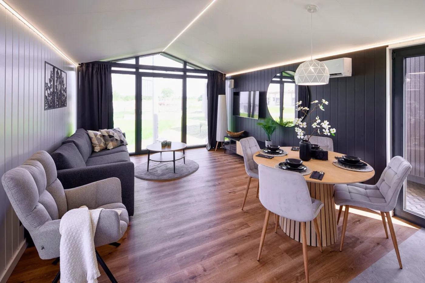 Interieur Modulodge model VELD woonruimte met zithoek, eettafel en grote ramen met uitzicht op buitenruimte