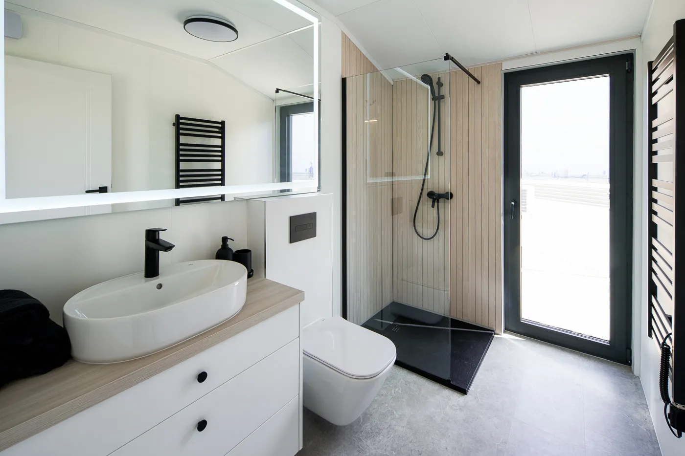 Interieur Modulodge model VELD badkamer met inloopdouche, wastafel, toilet en deur naar buiten met daglicht