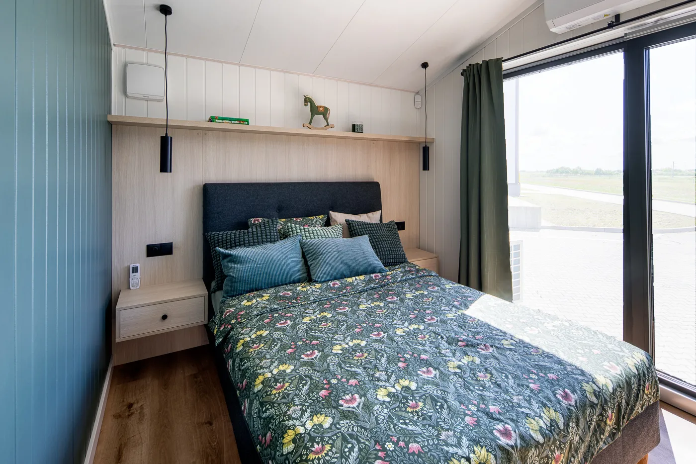 Interieur Modulodge model VELD slaapkamer met tweepersoonsbed, houten wandafwerking en grote ramen met daglicht