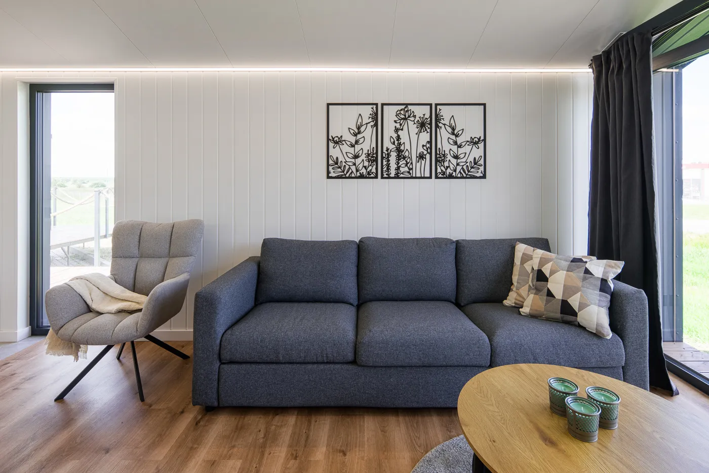 Interieur Modulodge model VELD zithoek met bank, fauteuil en grote ramen met natuurlijk daglicht